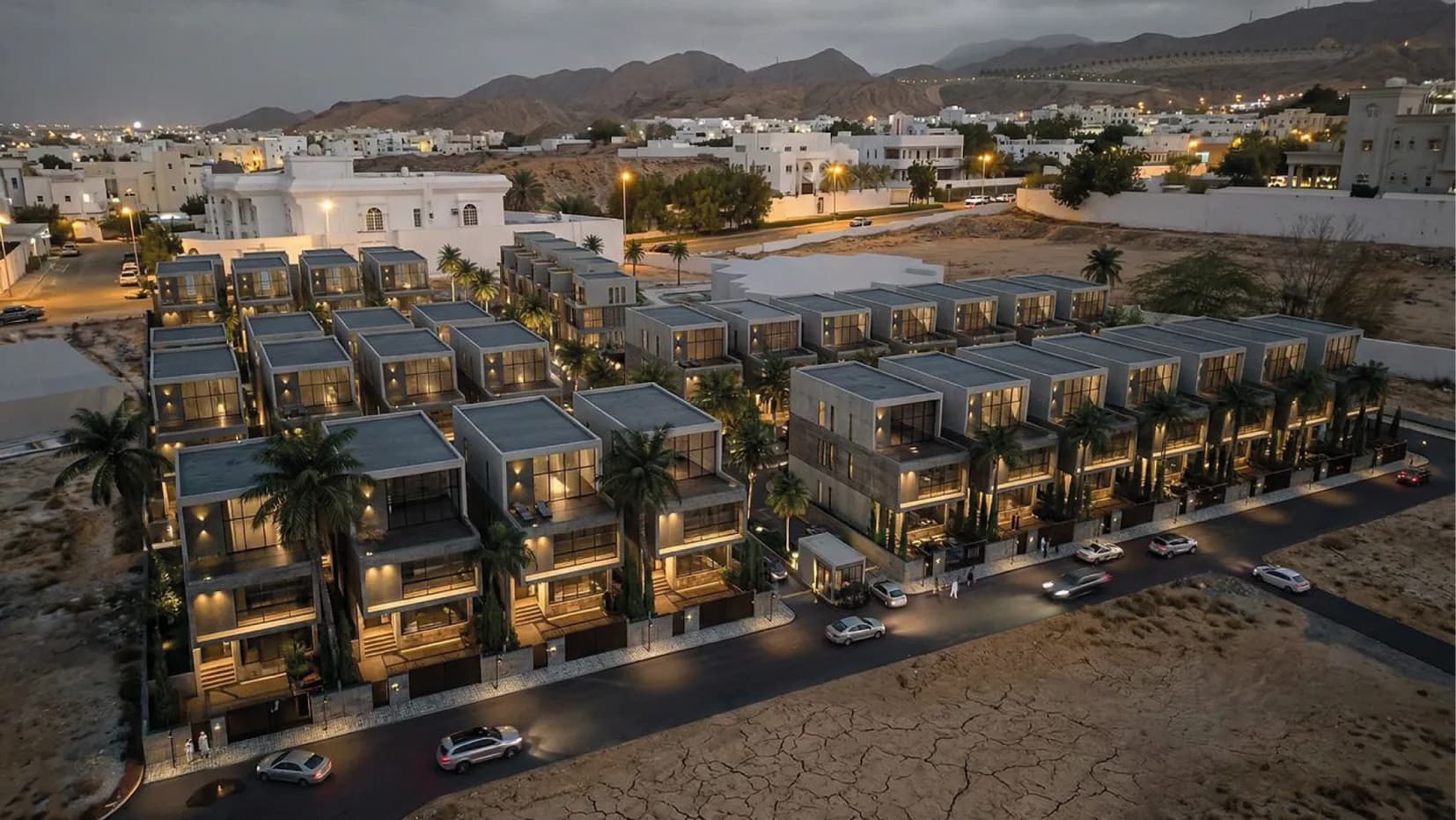Aerial view of Al Ilam Heights villas at dusk with the Muscat mountains behind